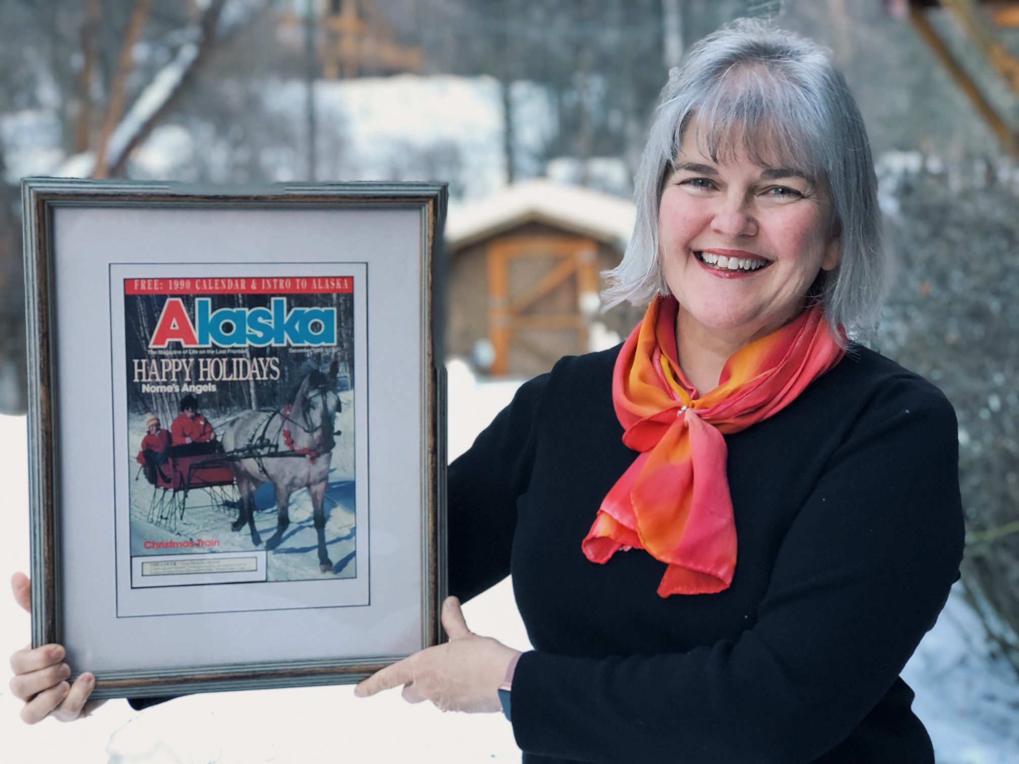 Gina holding framed copy of Dec. 1989 Alaska Magazine cover.